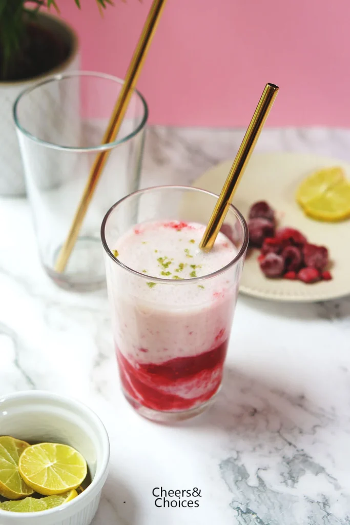 Himbeer-Smoothie "Cheesecake-Style" mit Limette und Quark, Himbeeren und Limettenscheiben im Hintergrund.