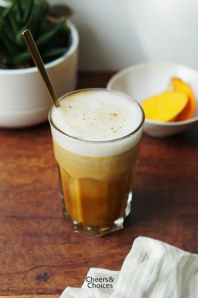 Kürbis-Latte in einem hohen Glas mit Löffel.